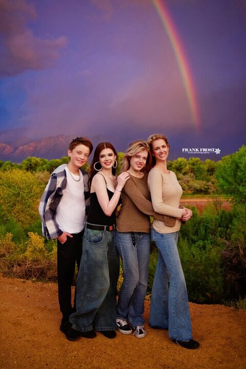 mom and high school aged children standing by the river during a rain storm with a rainbow over the mountains
in Albuquerque
